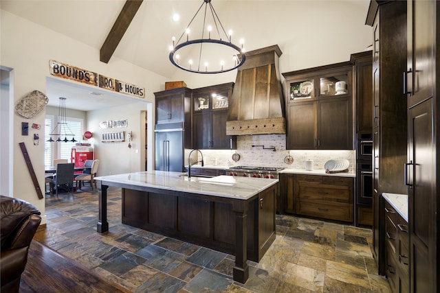 kitchen with a kitchen island with sink, sink, a notable chandelier, and dark brown cabinets