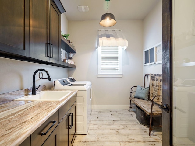 laundry area with cabinets, washer and clothes dryer, sink, and light hardwood / wood-style flooring