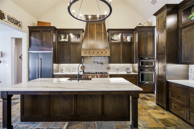 kitchen with decorative backsplash, vaulted ceiling, custom range hood, and built in fridge