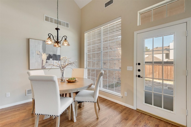 dining area with hardwood / wood-style floors, an inviting chandelier, and lofted ceiling