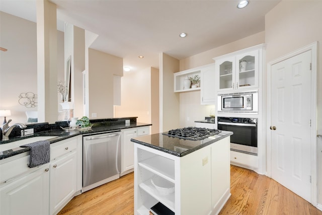 kitchen with stainless steel appliances, white cabinets, dark stone counters, and kitchen peninsula