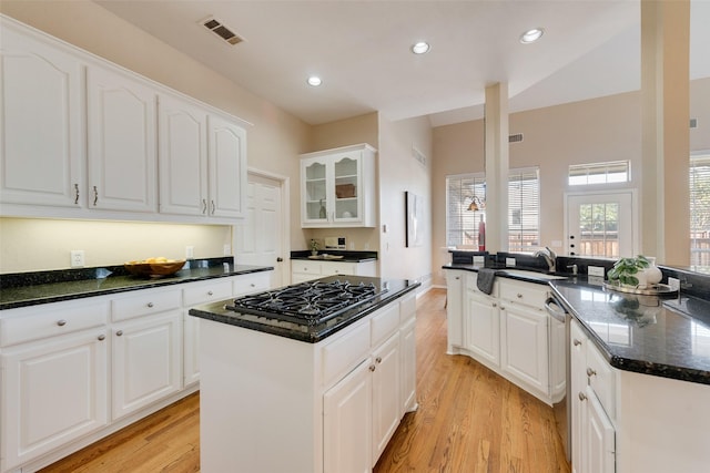 kitchen featuring a center island, dark stone counters, white cabinets, light hardwood / wood-style flooring, and sink