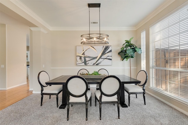 dining room featuring a notable chandelier, light colored carpet, and ornamental molding