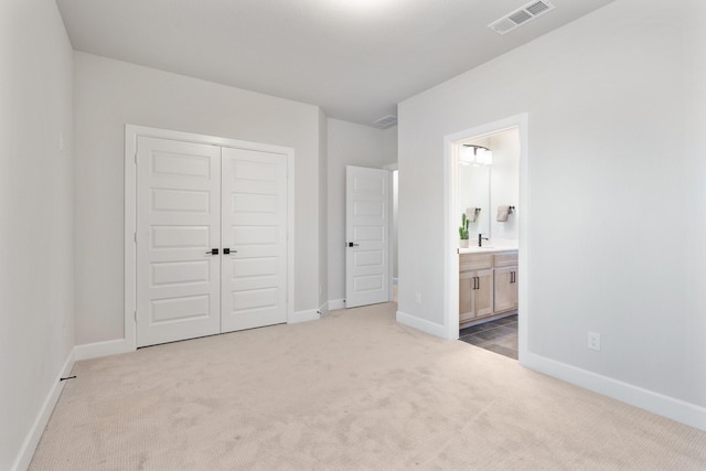 unfurnished bedroom featuring light colored carpet, connected bathroom, and a closet