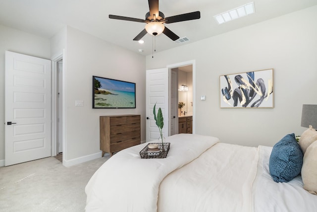 bedroom with light colored carpet, ceiling fan, and connected bathroom