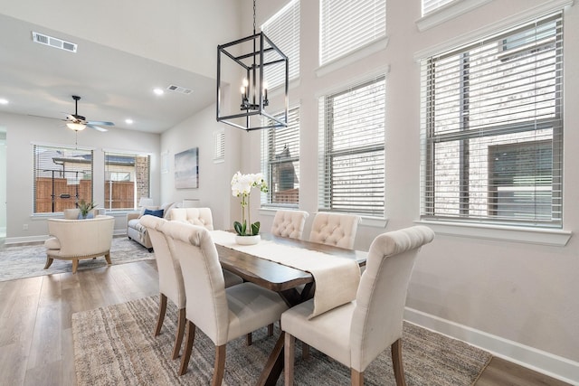 dining area featuring ceiling fan with notable chandelier and hardwood / wood-style flooring