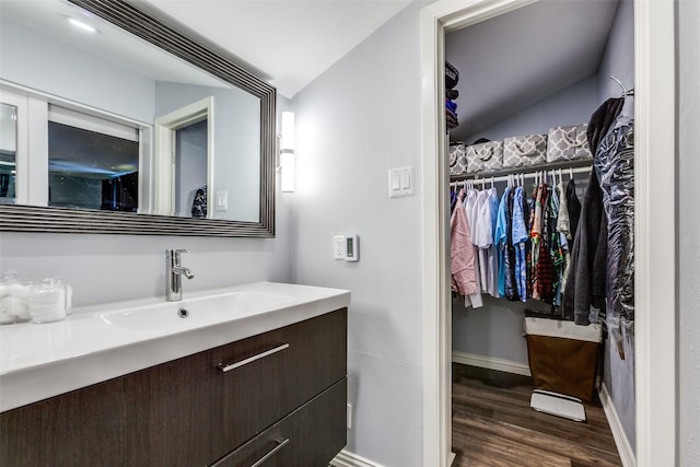 bathroom with lofted ceiling, vanity, and wood-type flooring