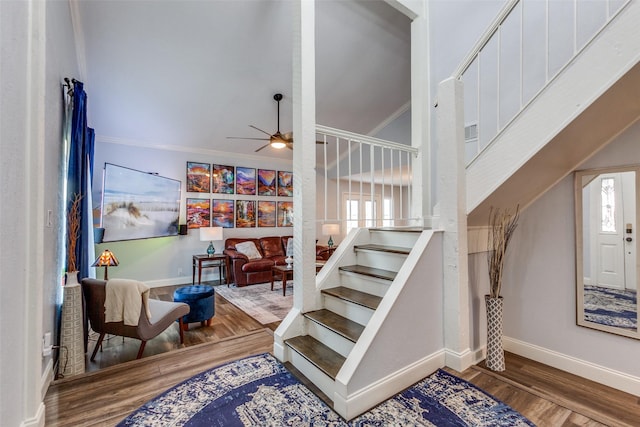 staircase featuring ceiling fan, vaulted ceiling, crown molding, and wood-type flooring