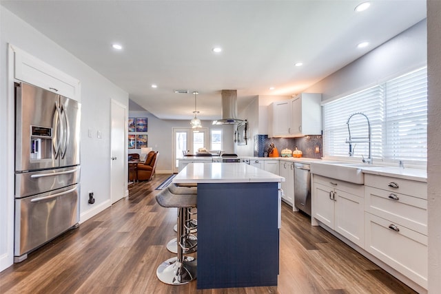 kitchen featuring a kitchen breakfast bar, appliances with stainless steel finishes, hanging light fixtures, a kitchen island, and white cabinets