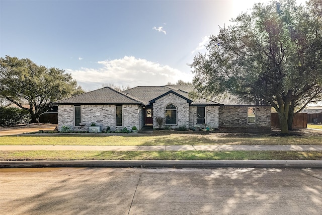 french country home with brick siding, a front yard, and fence