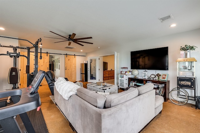 living room featuring ceiling fan and a barn door