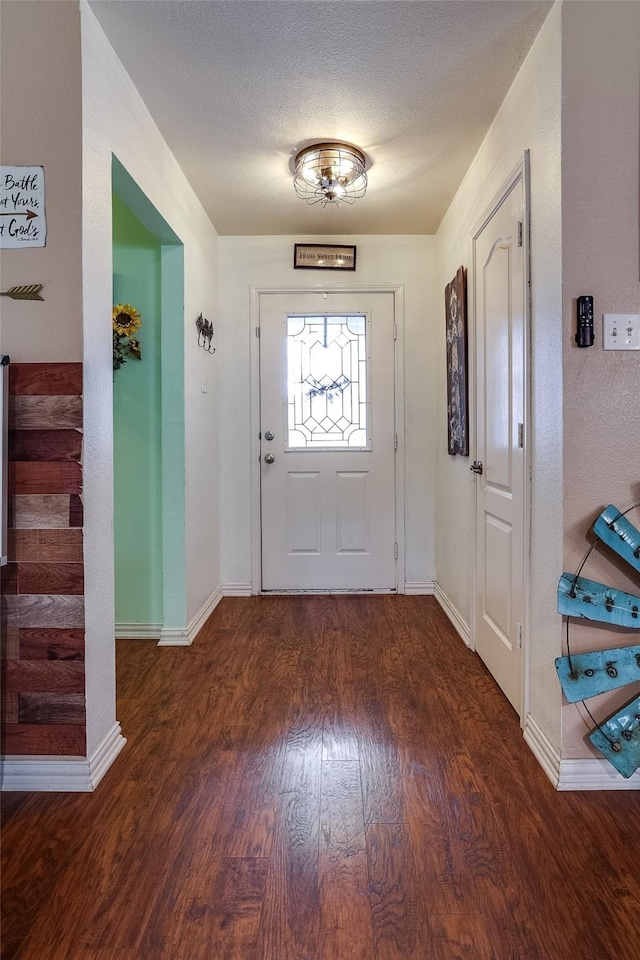 foyer entrance featuring a textured ceiling and dark wood-type flooring