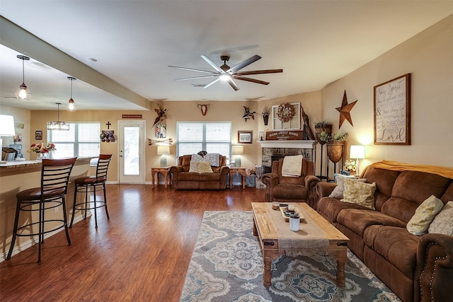 living room featuring a healthy amount of sunlight, dark hardwood / wood-style flooring, a high end fireplace, and ceiling fan with notable chandelier