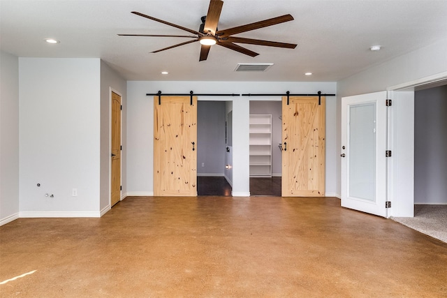 interior space featuring baseboards, a barn door, visible vents, and concrete flooring