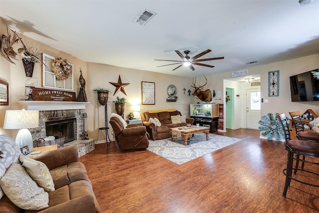 living room with a fireplace, ceiling fan, and wood-type flooring