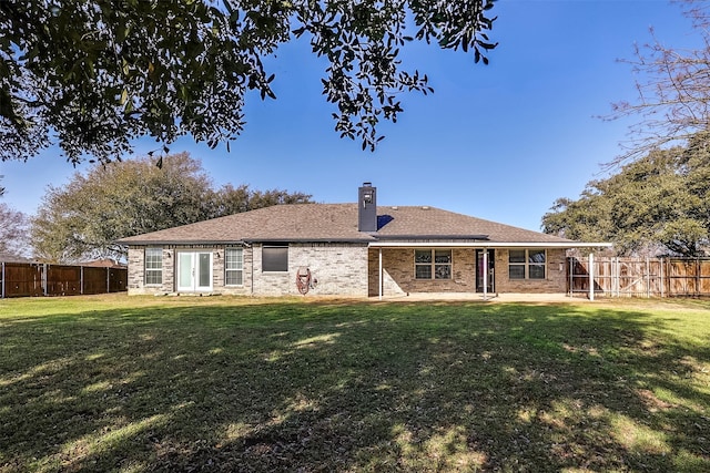 rear view of house with a yard, brick siding, a chimney, and a fenced backyard