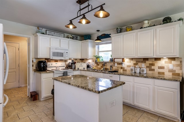 kitchen with white appliances, white cabinetry, and a kitchen island