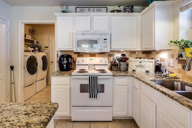 kitchen with white appliances, tasteful backsplash, white cabinets, washing machine and clothes dryer, and sink