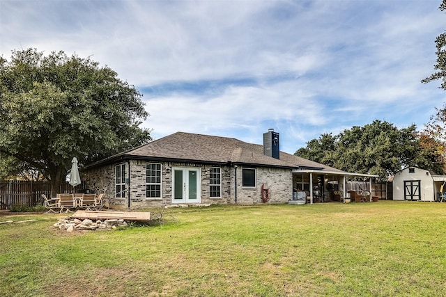 back of property featuring french doors, a yard, and a storage shed