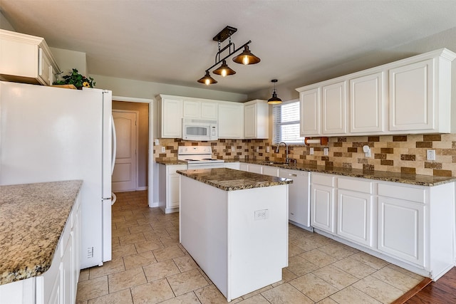 kitchen featuring white appliances, tasteful backsplash, white cabinets, a kitchen island, and a sink