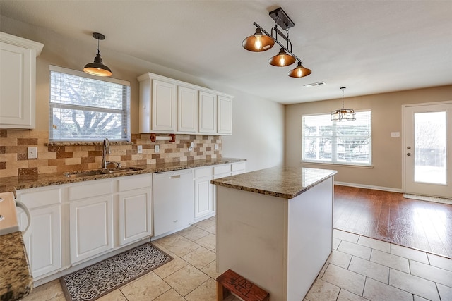 kitchen featuring tasteful backsplash, visible vents, a sink, a kitchen island, and dishwasher