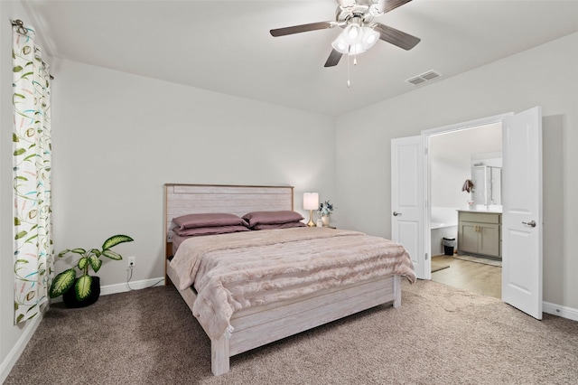 bedroom featuring ceiling fan, light colored carpet, and connected bathroom