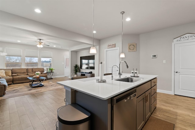 kitchen featuring dishwasher, a kitchen island with sink, hanging light fixtures, ceiling fan, and sink