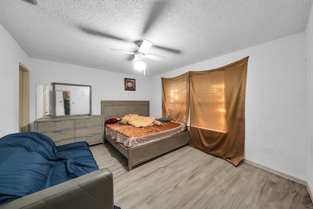 bedroom with ceiling fan, light wood-type flooring, and a textured ceiling