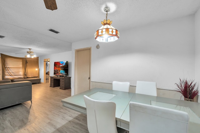 dining space featuring a textured ceiling, ceiling fan, and light hardwood / wood-style flooring