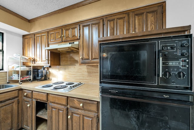 kitchen featuring a textured ceiling, tasteful backsplash, oven, crown molding, and white cooktop