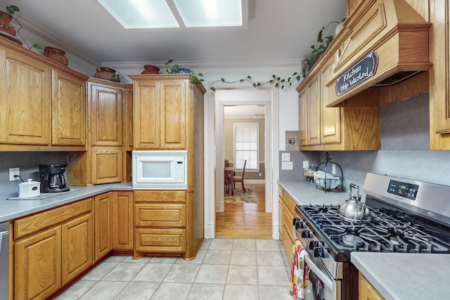 kitchen with custom exhaust hood, backsplash, ornamental molding, appliances with stainless steel finishes, and light tile patterned flooring