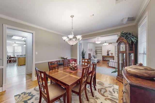 dining space featuring ornamental molding, a healthy amount of sunlight, light wood-type flooring, and ceiling fan with notable chandelier