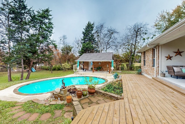 view of pool with a wooden deck, a lawn, and an outdoor structure