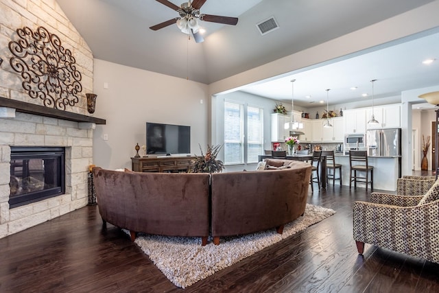 living room with ceiling fan, dark hardwood / wood-style flooring, vaulted ceiling, and a fireplace