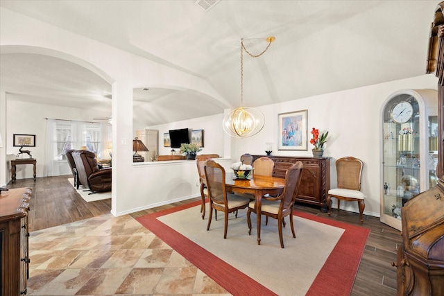 dining space with hardwood / wood-style floors, vaulted ceiling, and ceiling fan with notable chandelier