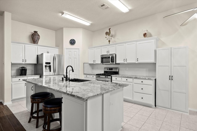 kitchen featuring appliances with stainless steel finishes, white cabinetry, a kitchen island with sink, and sink