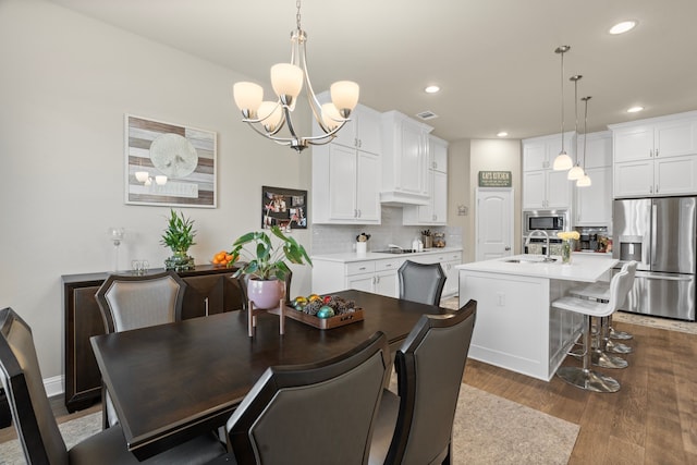 dining space with dark wood-type flooring, a chandelier, and sink