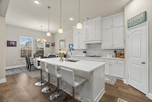 kitchen with pendant lighting, decorative backsplash, a kitchen island with sink, white cabinetry, and sink