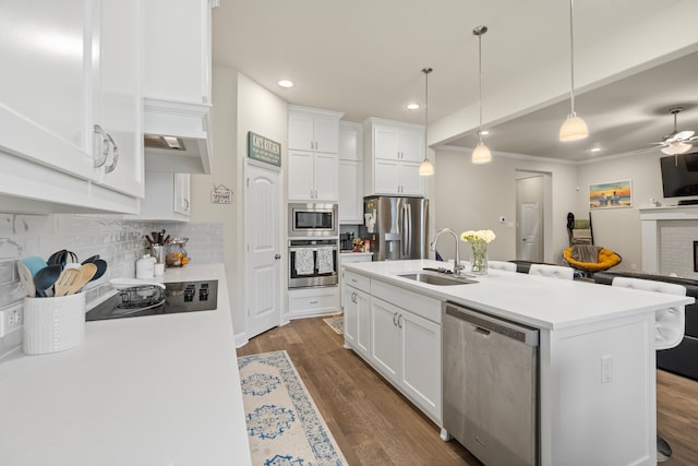 kitchen with sink, stainless steel appliances, white cabinetry, and a kitchen island with sink