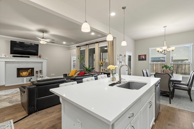 kitchen featuring white cabinets, a kitchen island with sink, sink, decorative light fixtures, and ceiling fan with notable chandelier