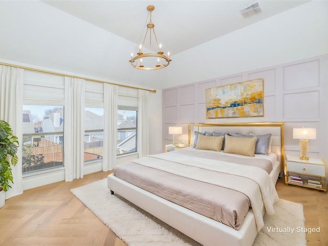 bedroom with light parquet flooring, multiple windows, and a notable chandelier