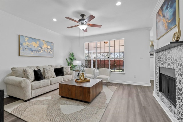 living room with ceiling fan, a fireplace, ornamental molding, and wood-type flooring