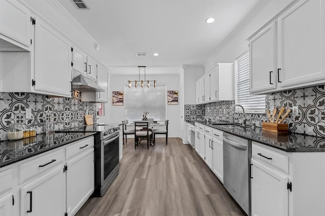 kitchen with decorative light fixtures, white cabinetry, sink, dark stone counters, and stainless steel appliances