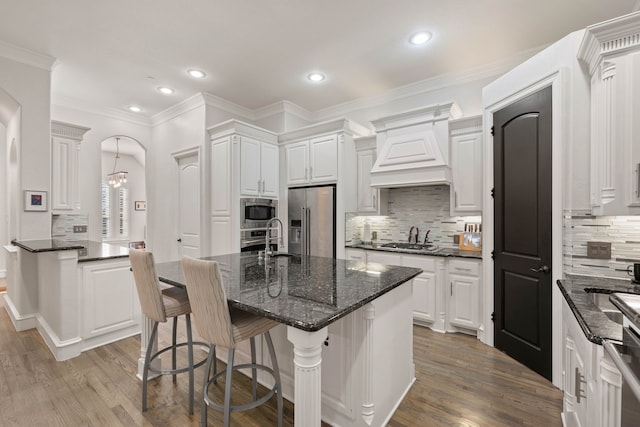 kitchen with appliances with stainless steel finishes, a center island, white cabinetry, dark stone countertops, and ceiling fan