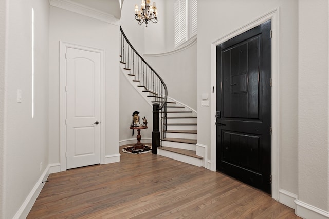 foyer entrance featuring hardwood / wood-style flooring, crown molding, and an inviting chandelier