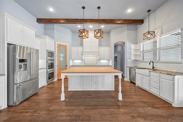 kitchen with decorative light fixtures, a kitchen island, sink, stainless steel appliances, and white cabinets