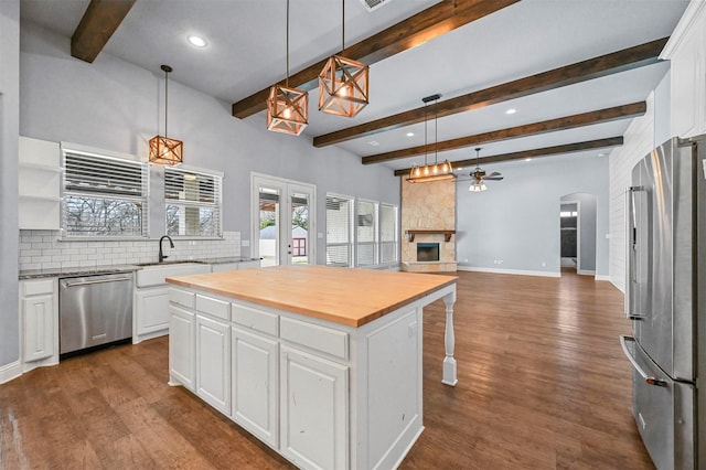 kitchen featuring white cabinets, appliances with stainless steel finishes, a center island, sink, and beam ceiling