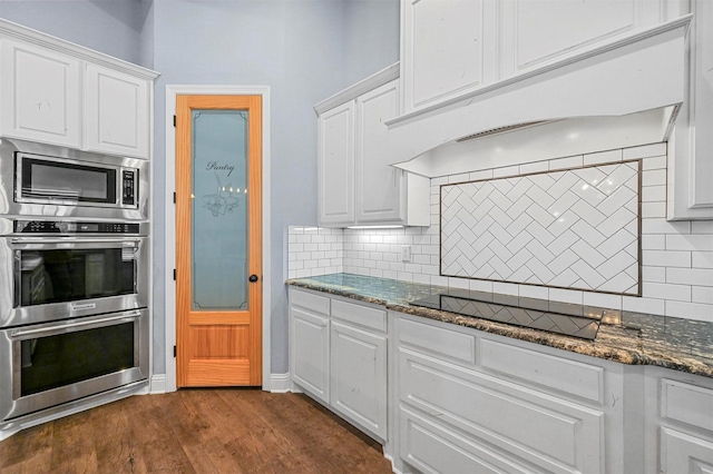 kitchen featuring decorative backsplash, premium range hood, white cabinetry, and appliances with stainless steel finishes