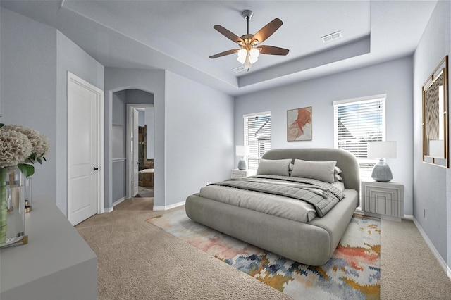 carpeted bedroom with ceiling fan, connected bathroom, and a tray ceiling