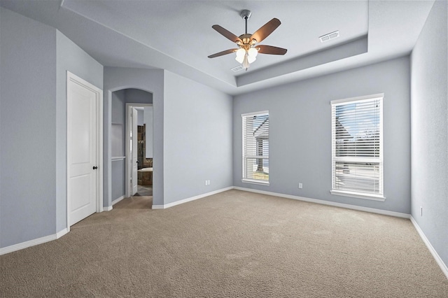 carpeted spare room featuring ceiling fan and a raised ceiling